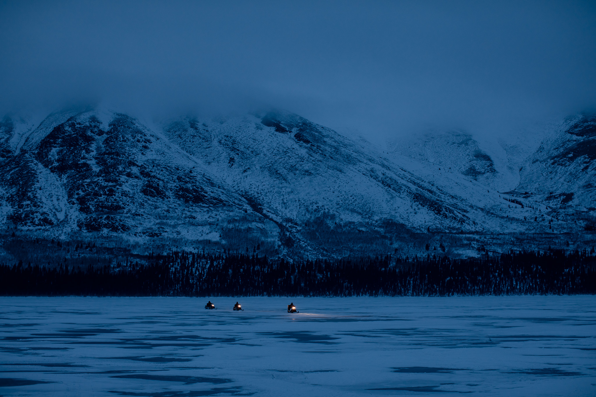 Snowmobiling at night on a frozen lake